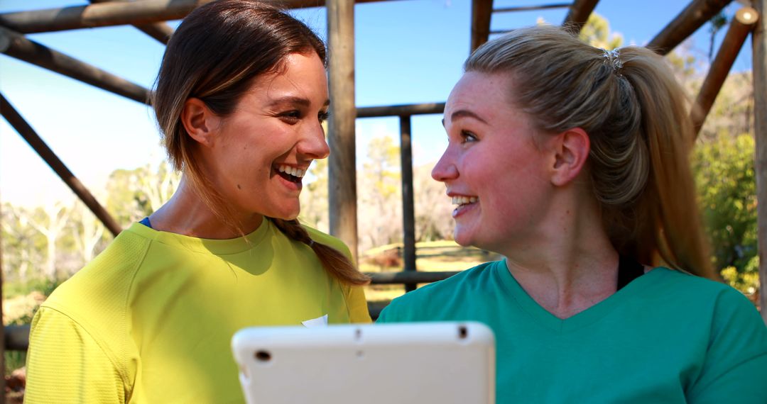 Two Happy Women Sharing a Joyful Moment Outdoors with Digital Tablet - Free Images, Stock Photos and Pictures on Pikwizard.com