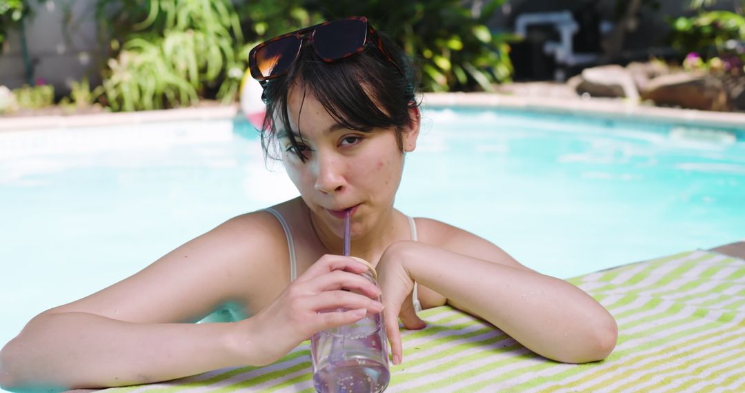 Asian Woman Relaxing at Poolside Sipping Drink with Straw