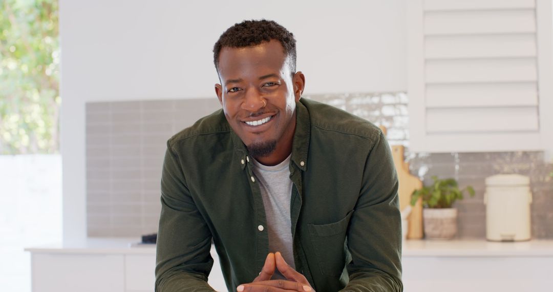 Smiling Young Man Leaning on Kitchen Counter in Modern Home