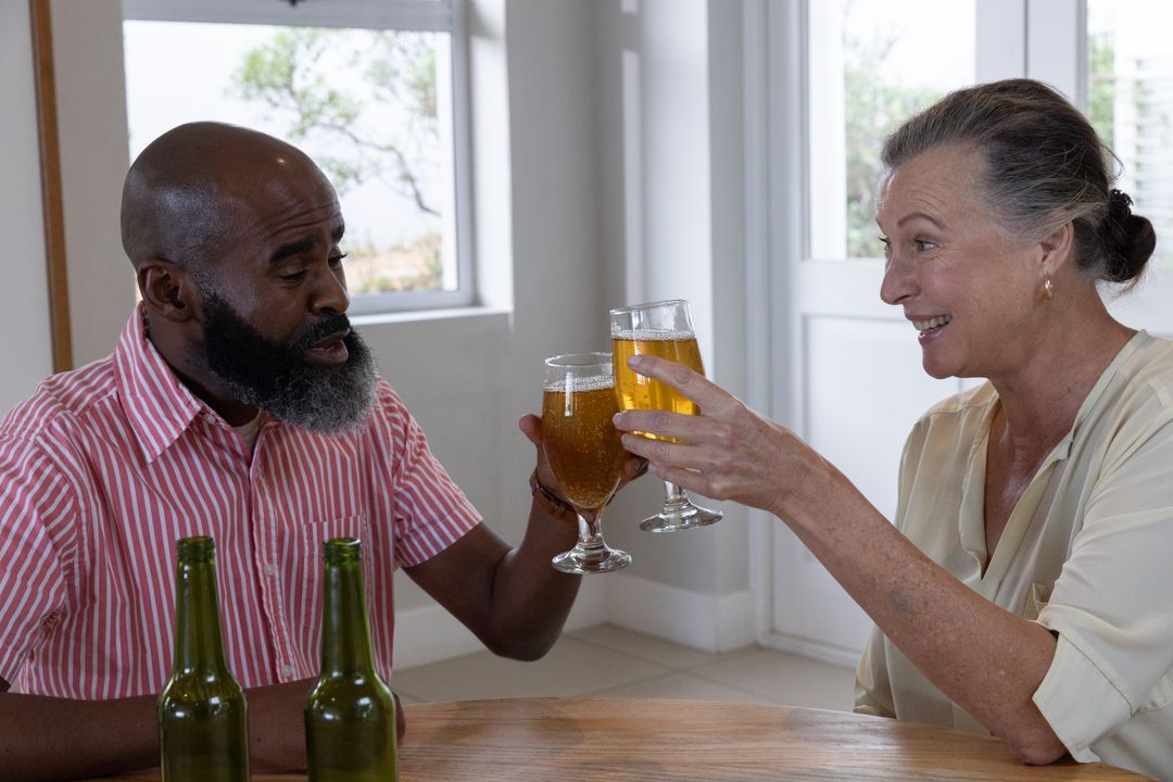 Senior Couple Toasting with Beer at Dinner in Cozy Home Setting