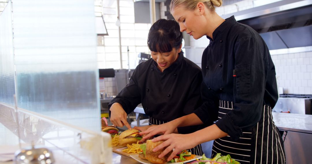 Two Female Chefs Preparing Gourmet Burgers in Modern Kitchen - Free Images, Stock Photos and Pictures on Pikwizard.com