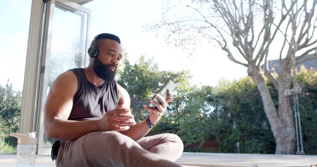 Man Using Smartphone and Relaxing Outdoors with Headphones - Free Images, Stock Photos and Pictures on Pikwizard.com