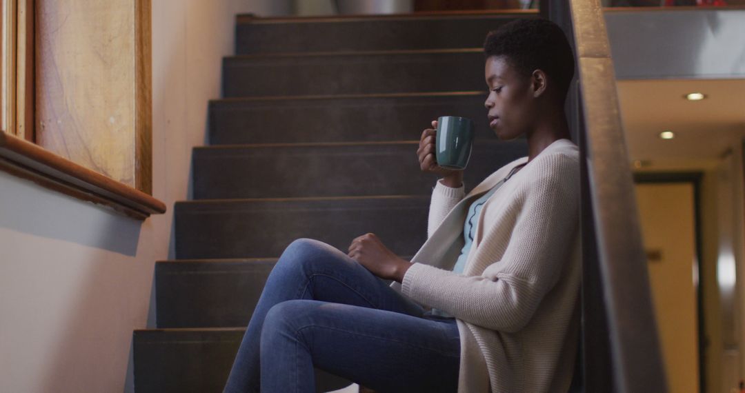 Pensive Woman Sipping Coffee on Stairs at Home - Free Images, Stock Photos and Pictures on Pikwizard.com