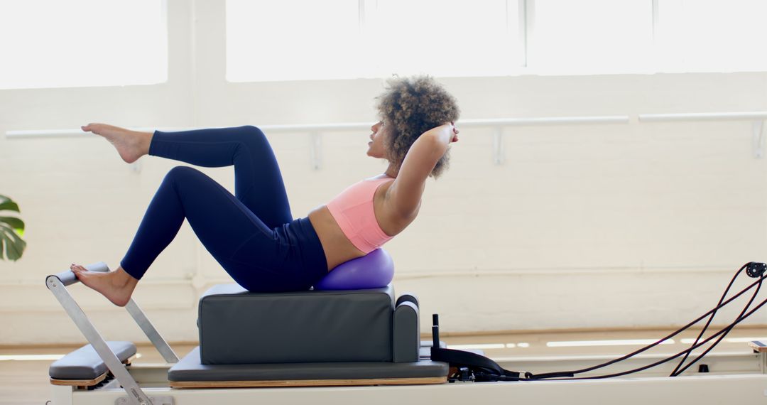 Woman Exercising on Pilates Reformer in Bright Studio