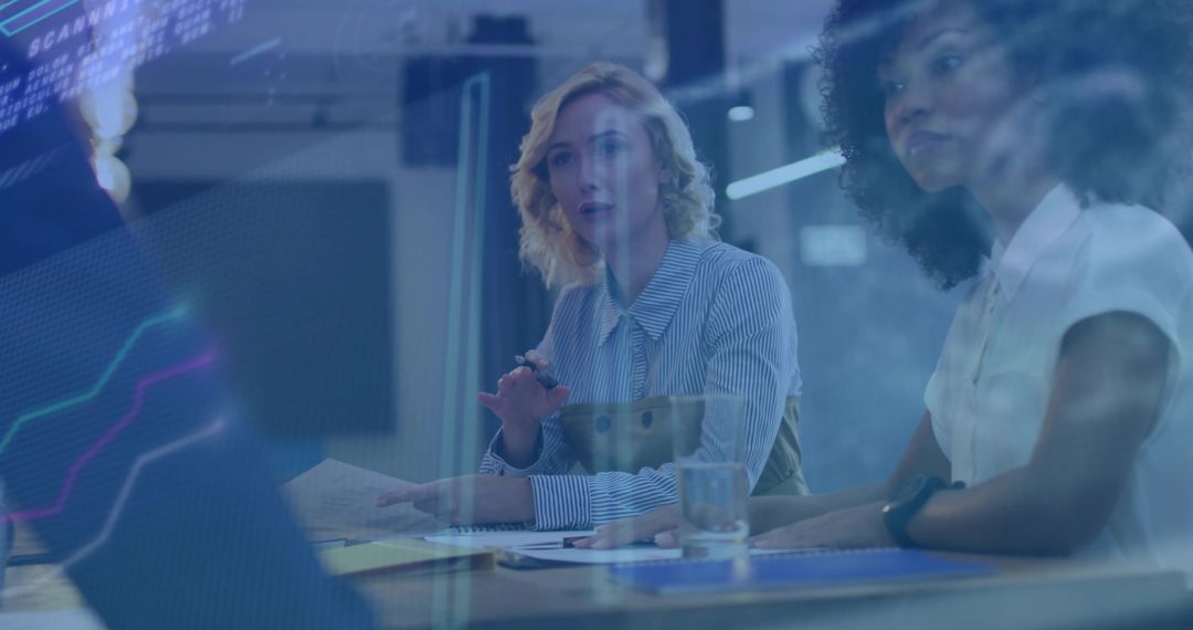 Two women collaborating and analyzing laptop data with glass reflection and charts