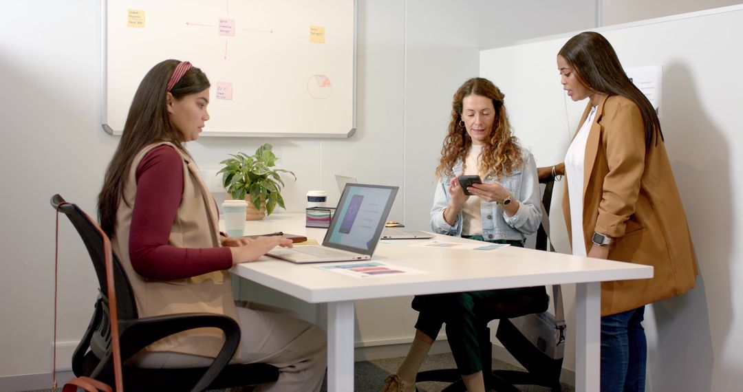 Female Team Collaborating in Modern Office with Laptops and Phone