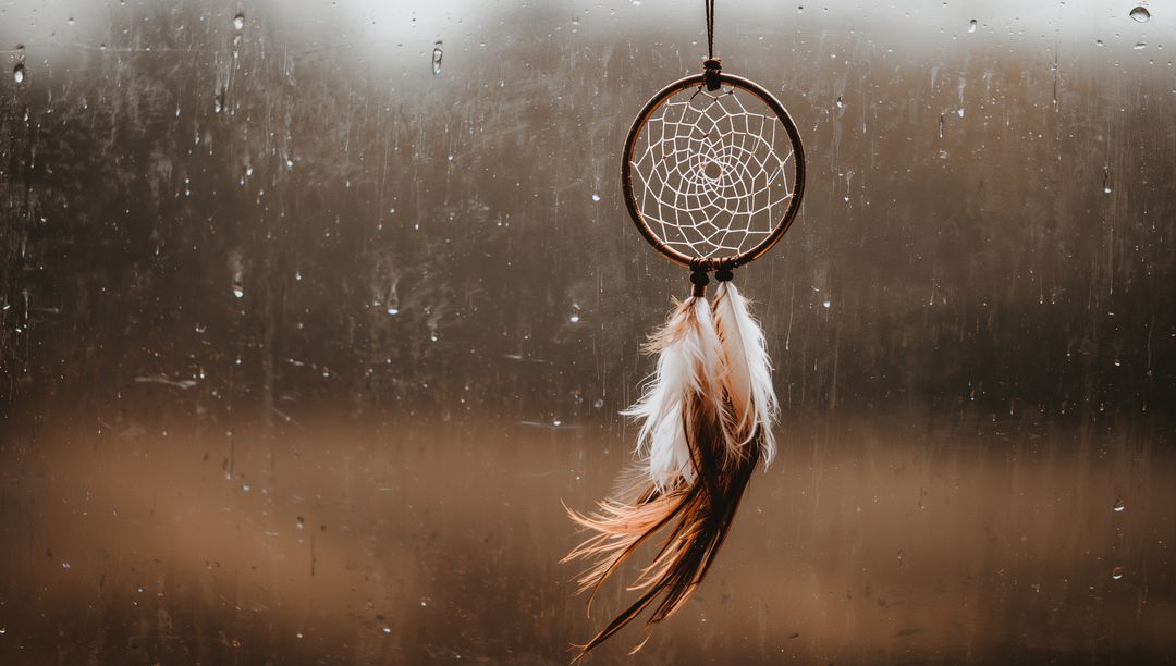 Dreamcatcher with Feathers Against Rainy Window Background