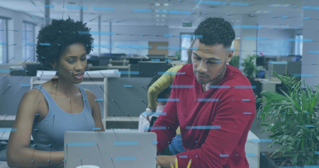 Collaborating coworkers reviewing digital project on laptop in modern open office