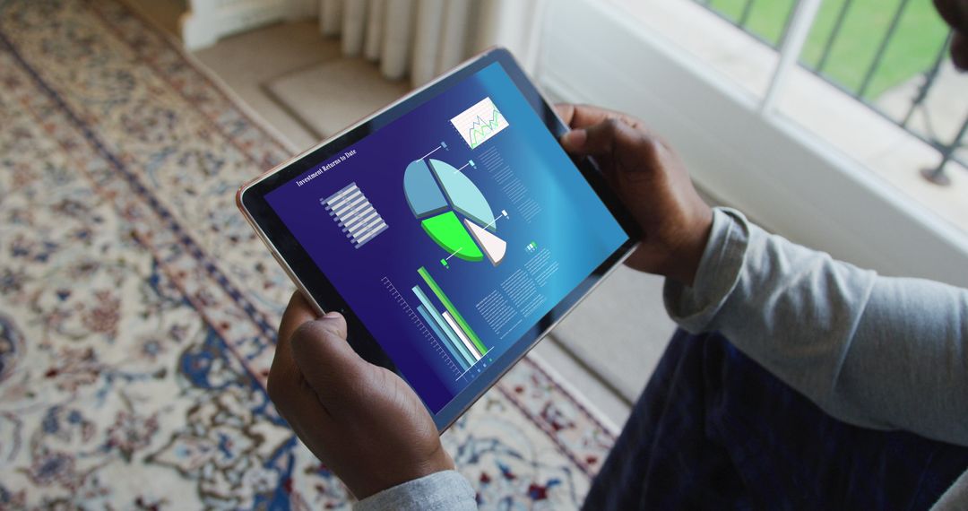 Person Analyzing Financial Data on Tablet Indoors