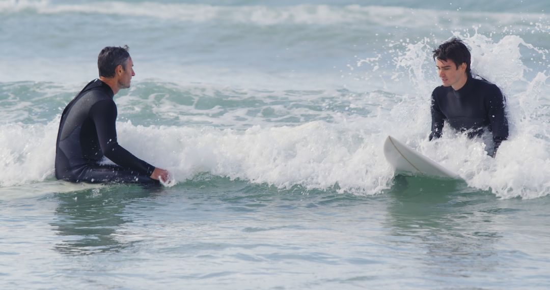 Two surfers enjoying waves in ocean, casually interacting - Free Images, Stock Photos and Pictures on Pikwizard.com