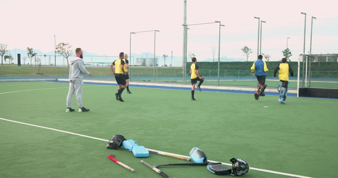 Diverse Field Hockey Team Practicing with Coach on Turf Pitch