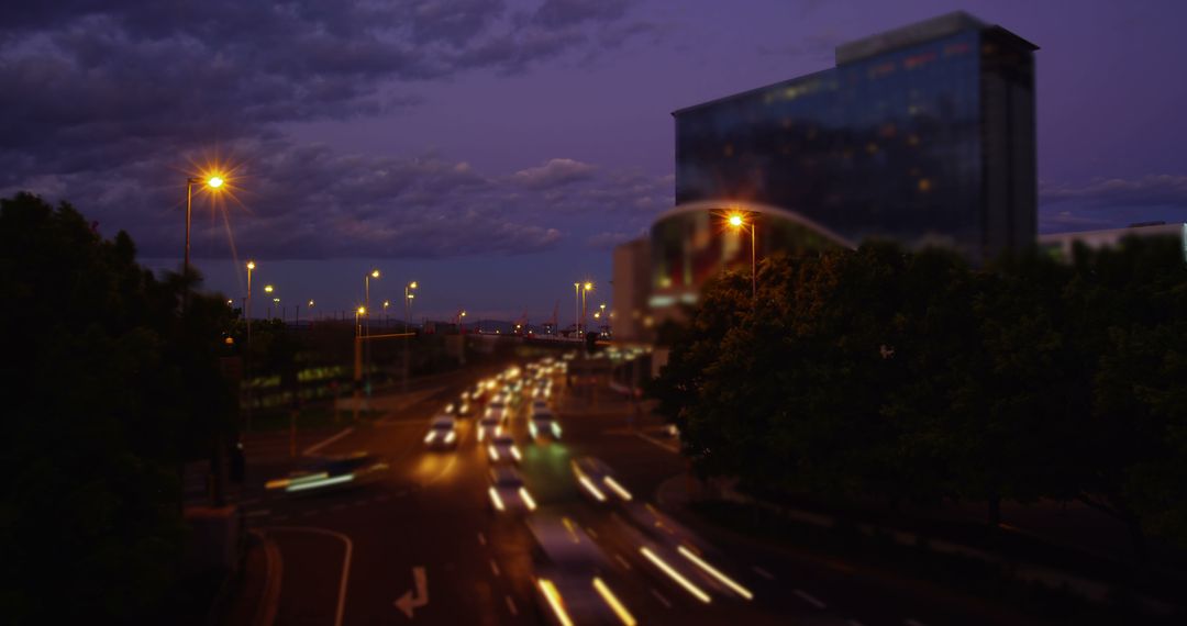 Busy Urban Road at Night with Blurred Vehicle Lights and Office Building - Free Images, Stock Photos and Pictures on Pikwizard.com