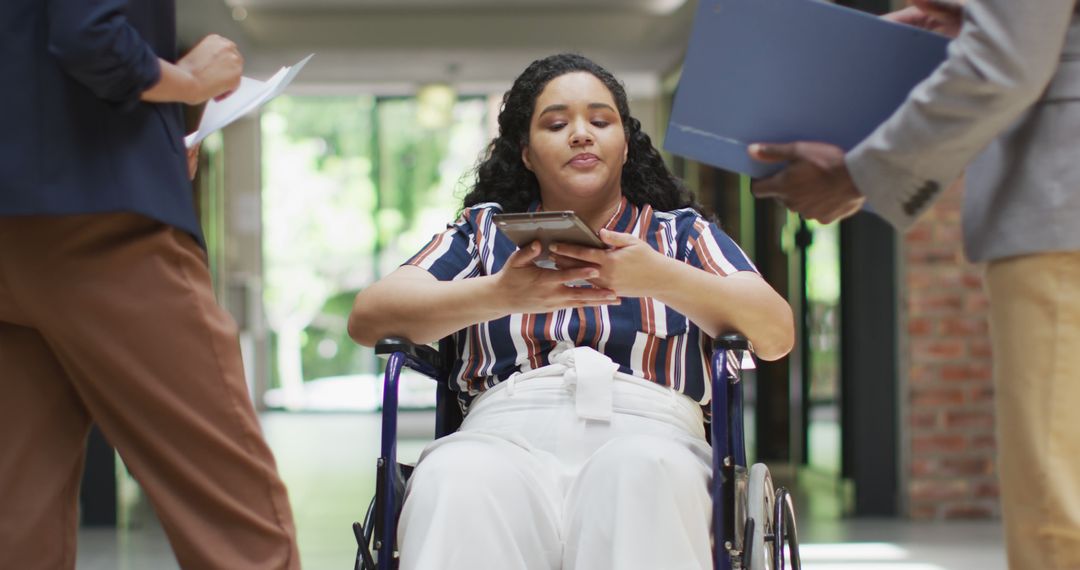 Focused Young Woman in Wheelchair Using Smartphone in Office Corridor - Free Images, Stock Photos and Pictures on Pikwizard.com