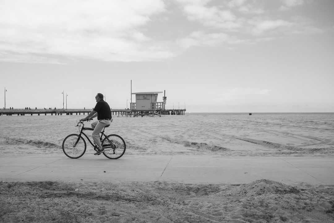 Person Riding Bicycle on Beachside Pathway Near Ocean - Free Images, Stock Photos and Pictures on Pikwizard.com