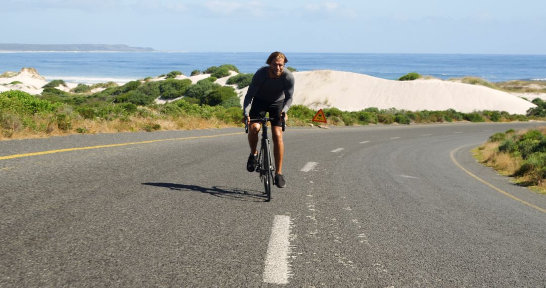 Man cycling on scenic coastal road on sunny day - Free Images, Stock Photos and Pictures on Pikwizard.com