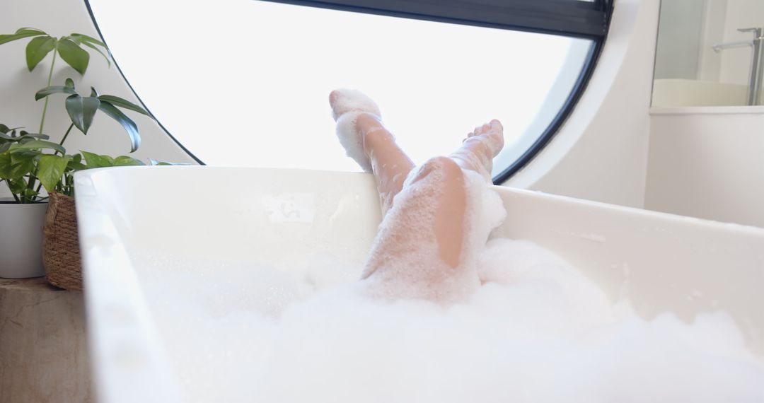 Relaxing in Foam-Filled Bathtub Near Large Circular Window