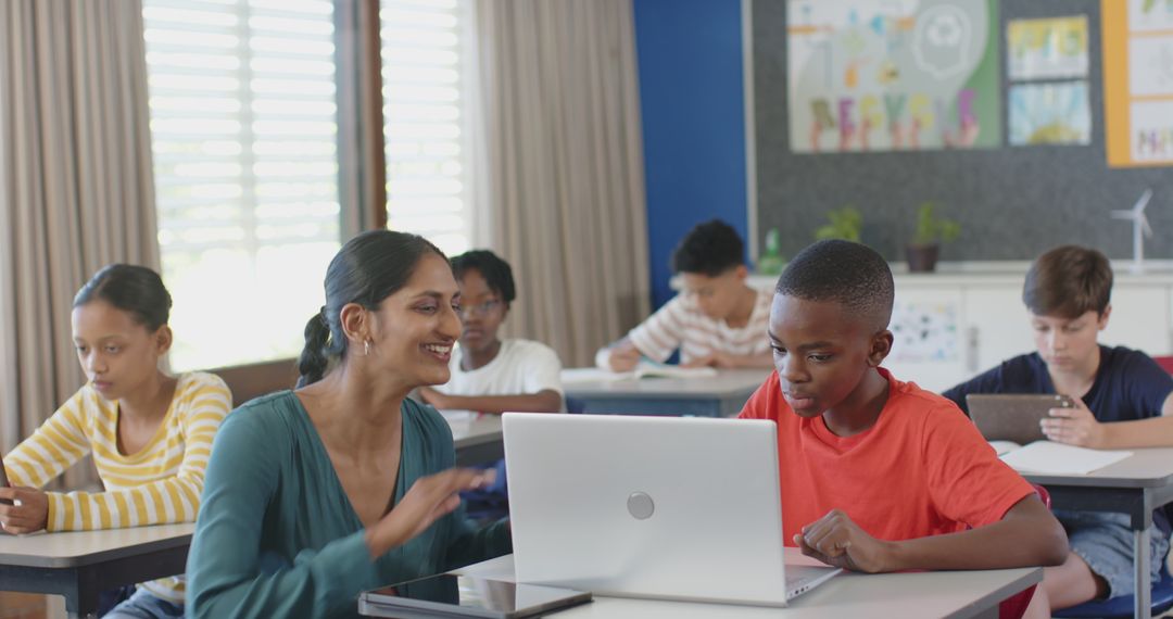 Teacher Assisting Student with Laptop in Inclusive Classroom Setting
