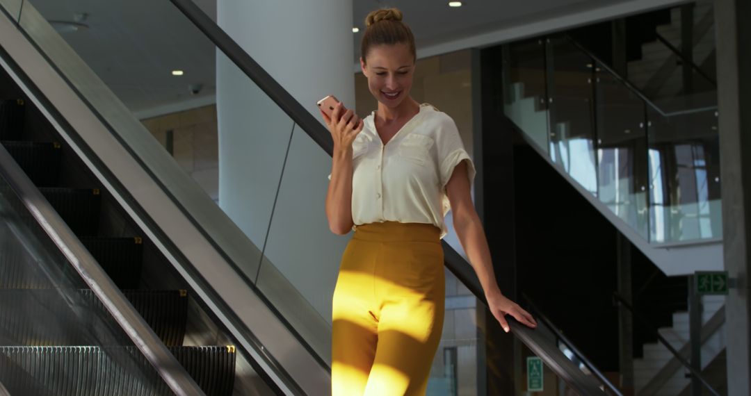 Businesswoman Walking Down Escalator While Using Smartphone - Free Images, Stock Photos and Pictures on Pikwizard.com