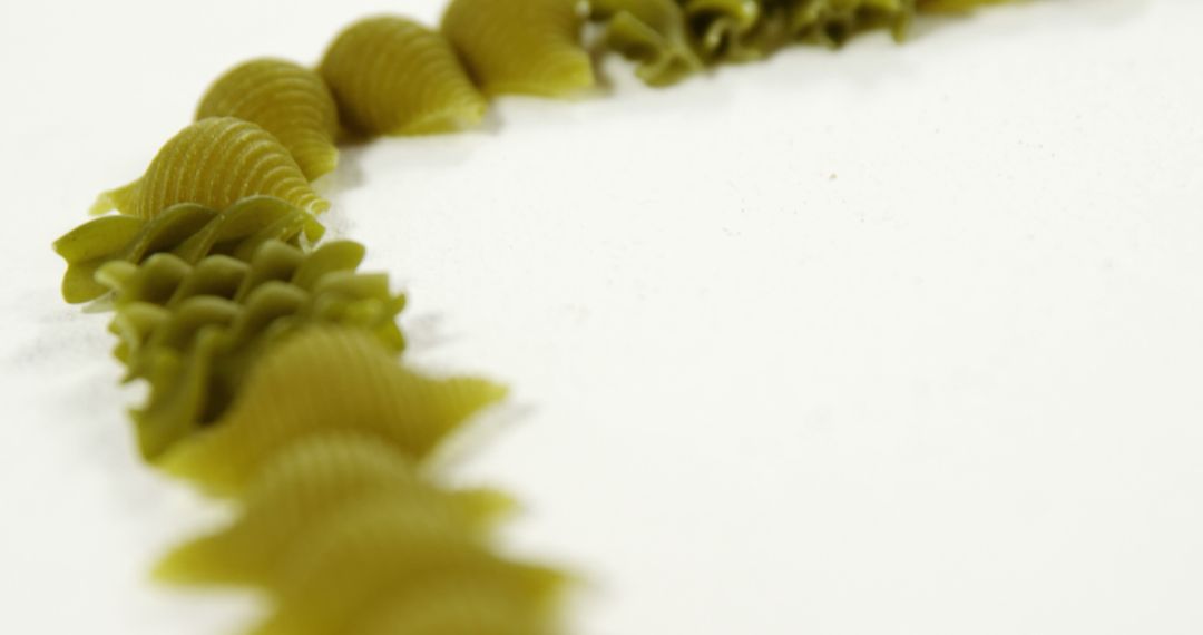 Close-Up of Green Pasta in Curved Arrangement on White Background - Free Images, Stock Photos and Pictures on Pikwizard.com