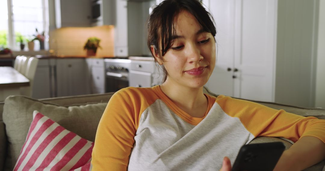 Woman Relaxing on Sofa Using Smartphone in Modern Kitchen-Living Space