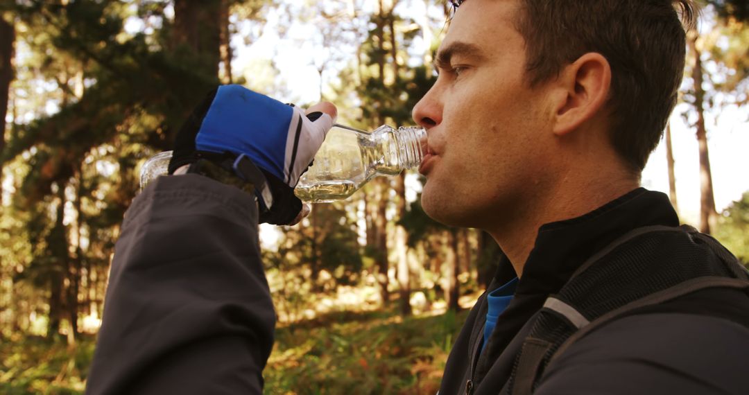 Man Hydrating During Hike in Forested Area with Glove and Jacket - Free Images, Stock Photos and Pictures on Pikwizard.com