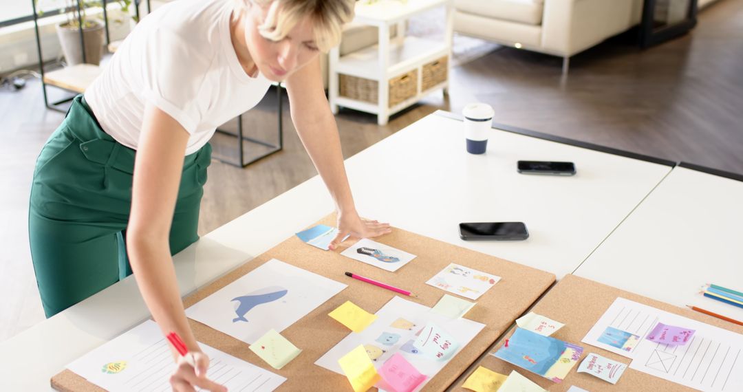Creative Designer Organizing Ideas on Cork Board in Modern Office