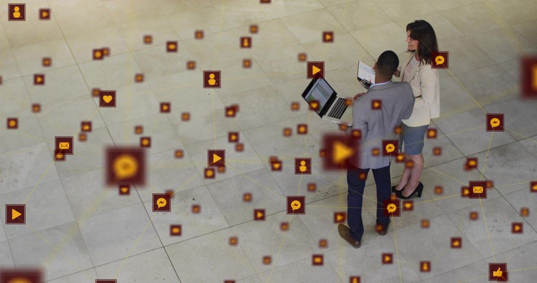 Business professionals collaborating over laptop with floating social media network icons