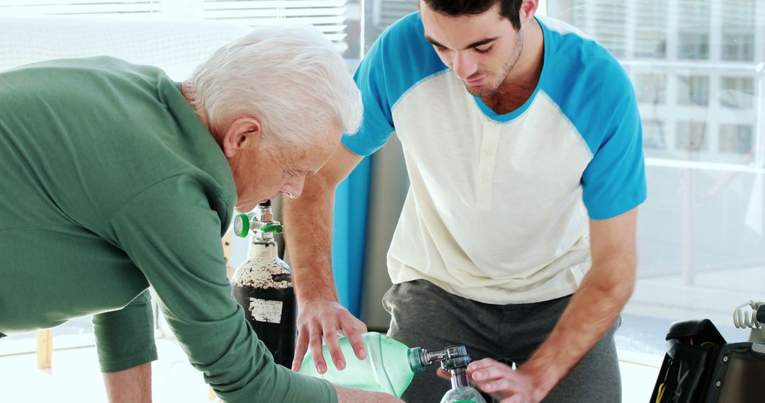 Elderly Man and Young Person Setting Up Medical Oxygen Equipment - Free Images, Stock Photos and Pictures on Pikwizard.com