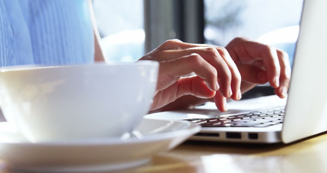 Woman Typing on Laptop in Coffee Shop