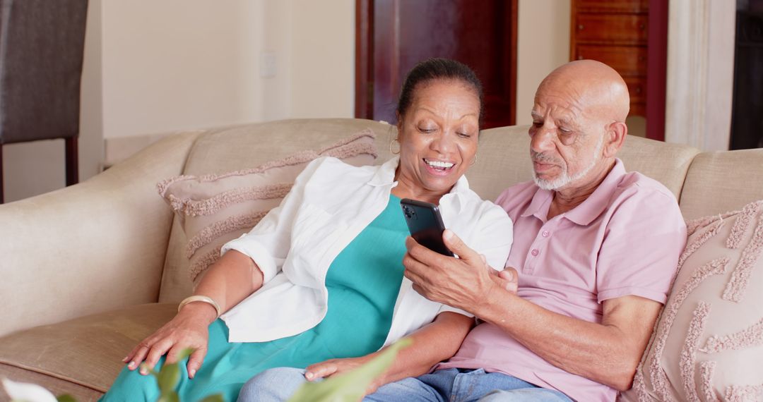 Senior Couple Relaxing on Sofa Enjoying Smartphone Together