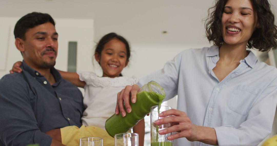 Happy Family in Kitchen Pouring Green Smoothie Together - Free Images, Stock Photos and Pictures on Pikwizard.com