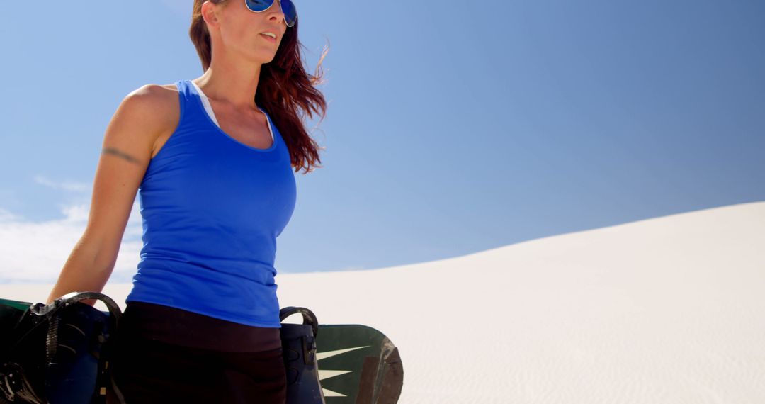 Woman with Snowboard in Sand Dunes on Sunny Day