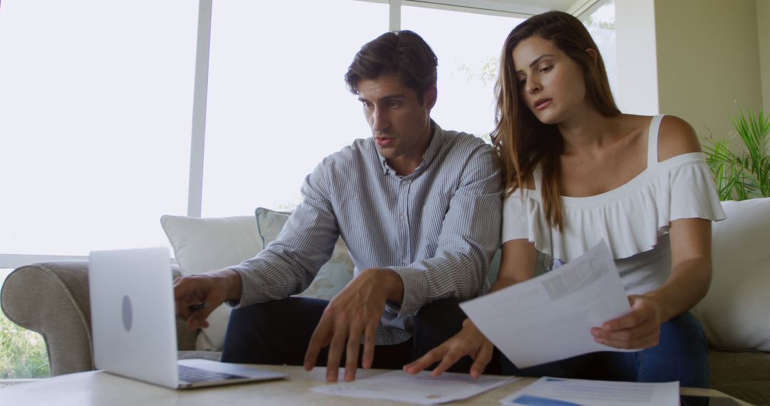 Serious Couple Discussing Bills Using Laptop at Home