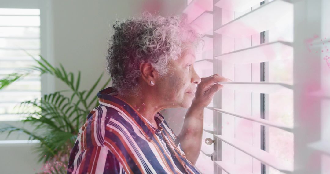 Serene Senior Woman Enjoying View Through Window Blinds