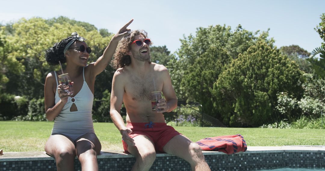 Diverse Couple Relaxing Poolside with Refreshing Drinks on Sunny Day