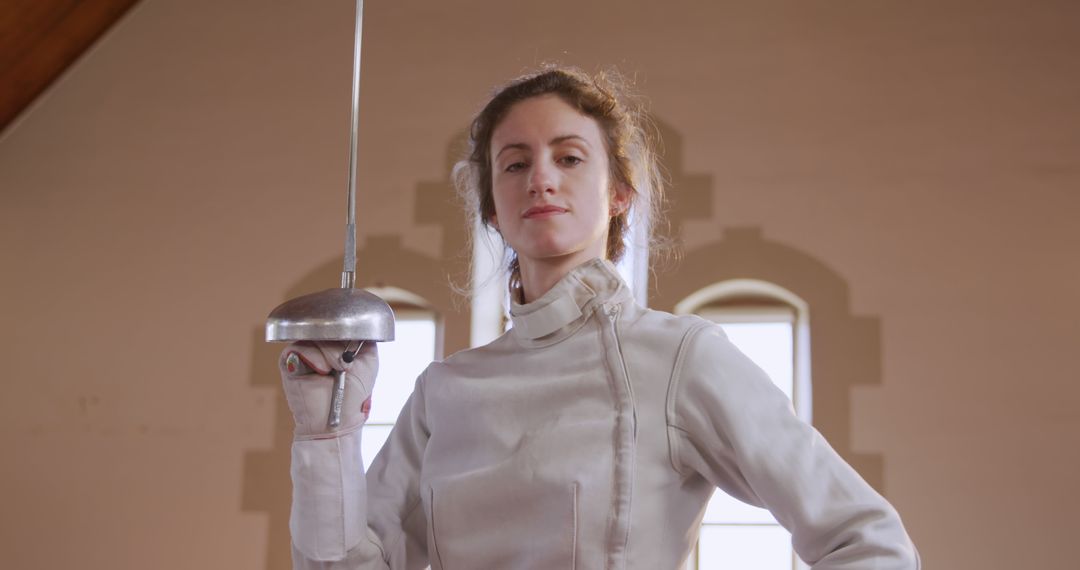 Confident Female Fencer in Protective Gear Holding Rapier Indoors - Free Images, Stock Photos and Pictures on Pikwizard.com