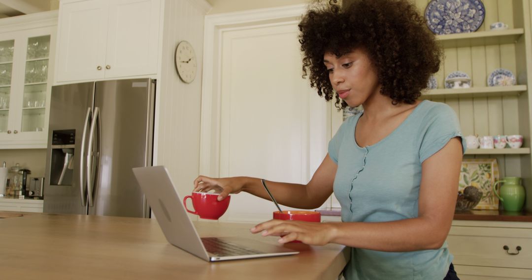 Biracial Woman Using Laptop While Having Breakfast in Modern Kitchen