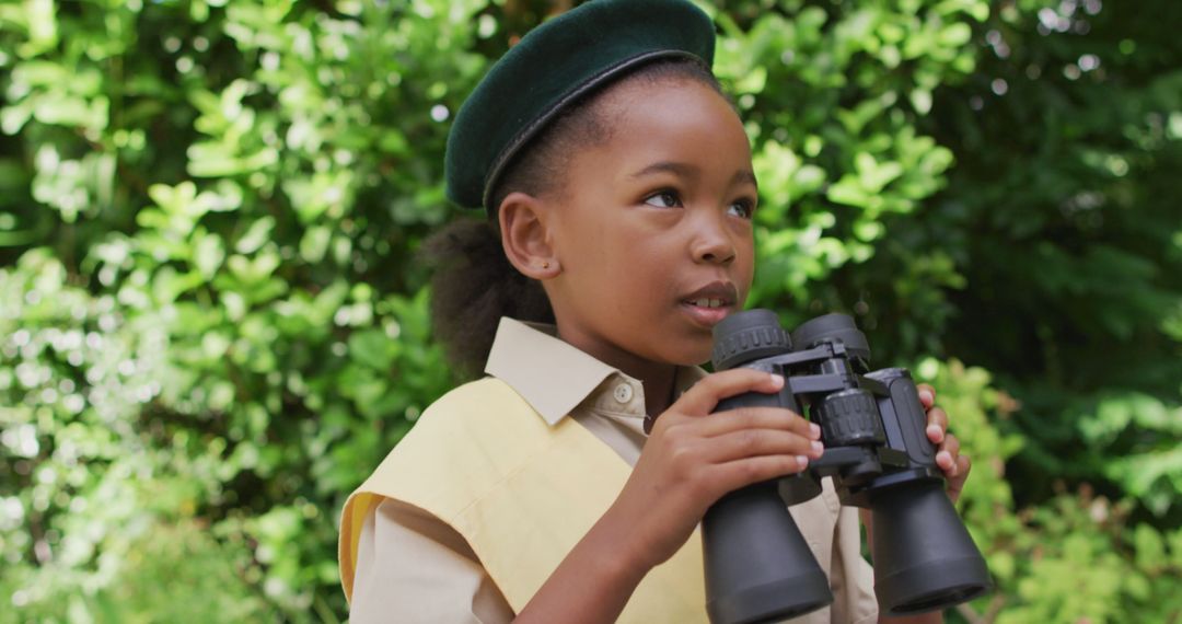 African American Girl Scout Using Binoculars in Lush Garden