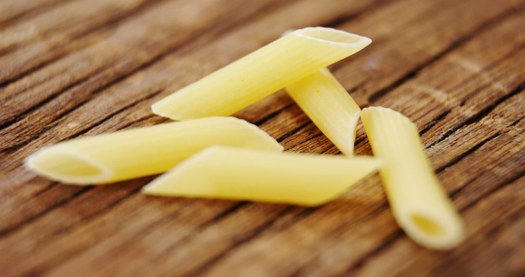 Close-Up of Raw Penne Pasta on Rustic Wooden Surface - Free Images, Stock Photos and Pictures on Pikwizard.com