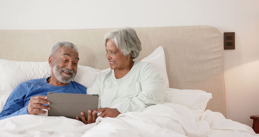 Happy Senior Couple Enjoying Tablet in Bed