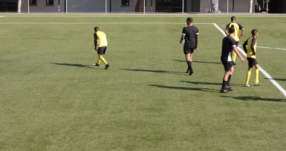 Soccer Players Strategizing During Friendly Match on Green Field