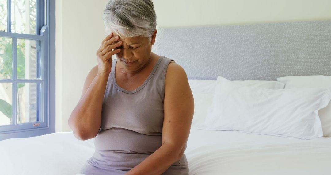 Elderly Woman Experiencing Discomfort While Sitting on Bed - Free Images, Stock Photos and Pictures on Pikwizard.com