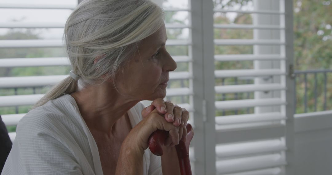 Thoughtful Senior Woman Looking Out Window at Home - Free Images, Stock Photos and Pictures on Pikwizard.com