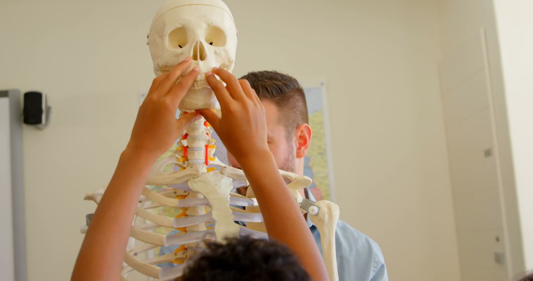 Teacher and Students Examining Skeleton Model in Classroom