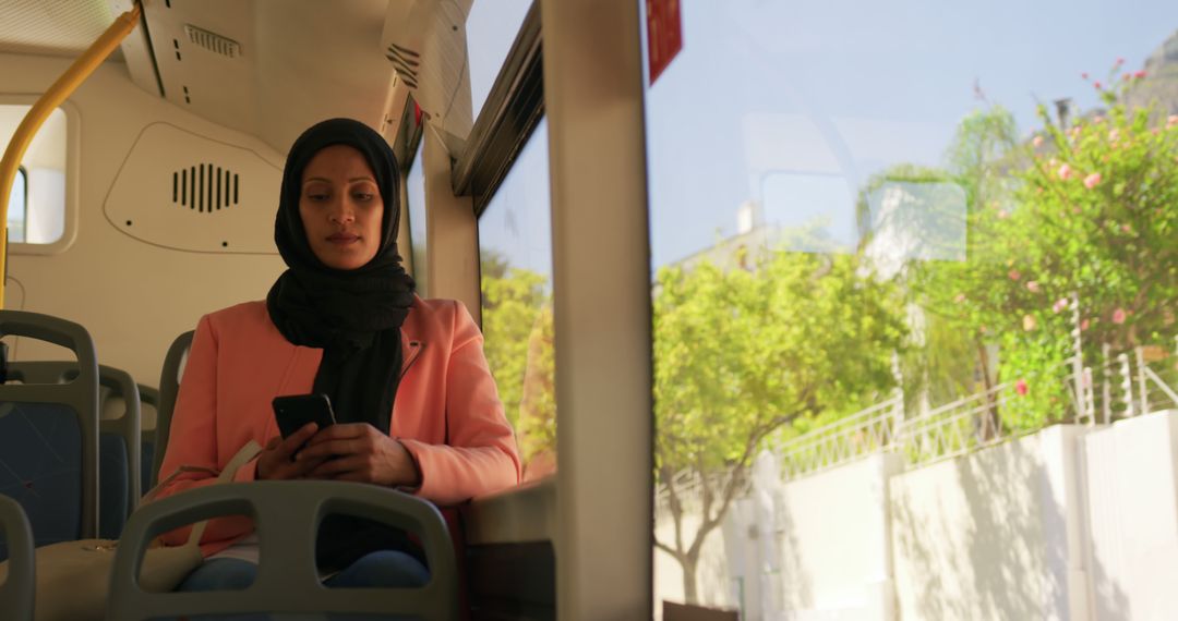 Young Woman in Hijab Using Smartphone on City Bus - Free Images, Stock Photos and Pictures on Pikwizard.com