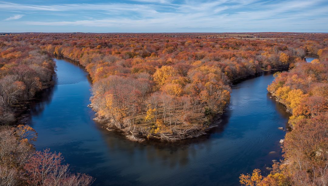 Autumn River Winding Around Wooded Peninsula with Golden Fall Foliage and Clear Sky