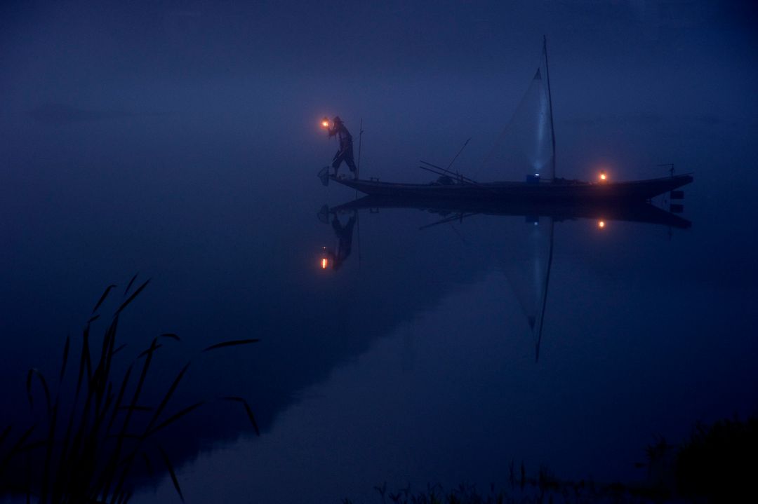 Fisherman On Traditional Boat Holding Lantern In Evening Fog - Free Images, Stock Photos and Pictures on Pikwizard.com