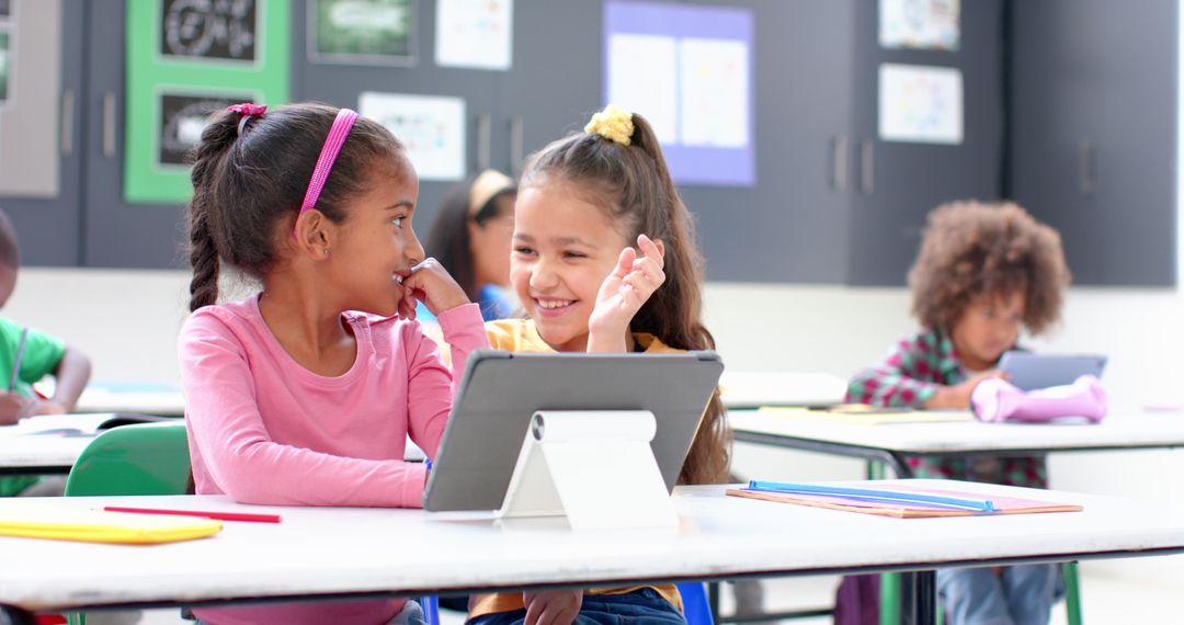 Two Girls Smiling and Learning with Tablet in Classroom Setting