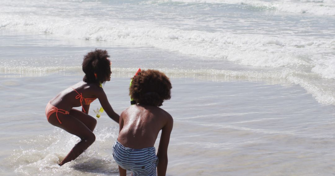 African american children wearing scuba goggles playing at the beach - Free Images, Stock Photos and Pictures on Pikwizard.com