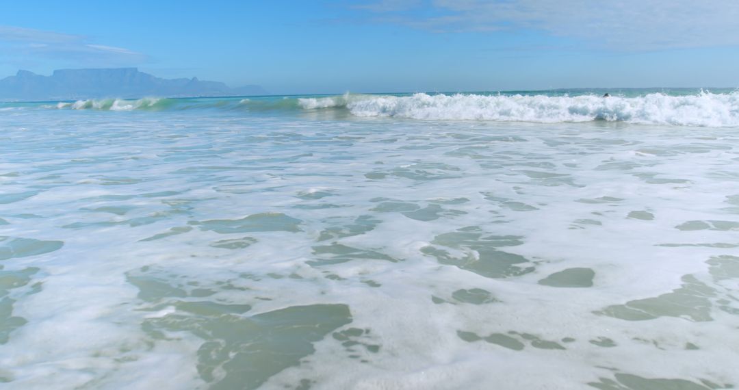 Calm Ocean Waves with Table Mountain in Background, Sunlit Shoreline - Free Images, Stock Photos and Pictures on Pikwizard.com